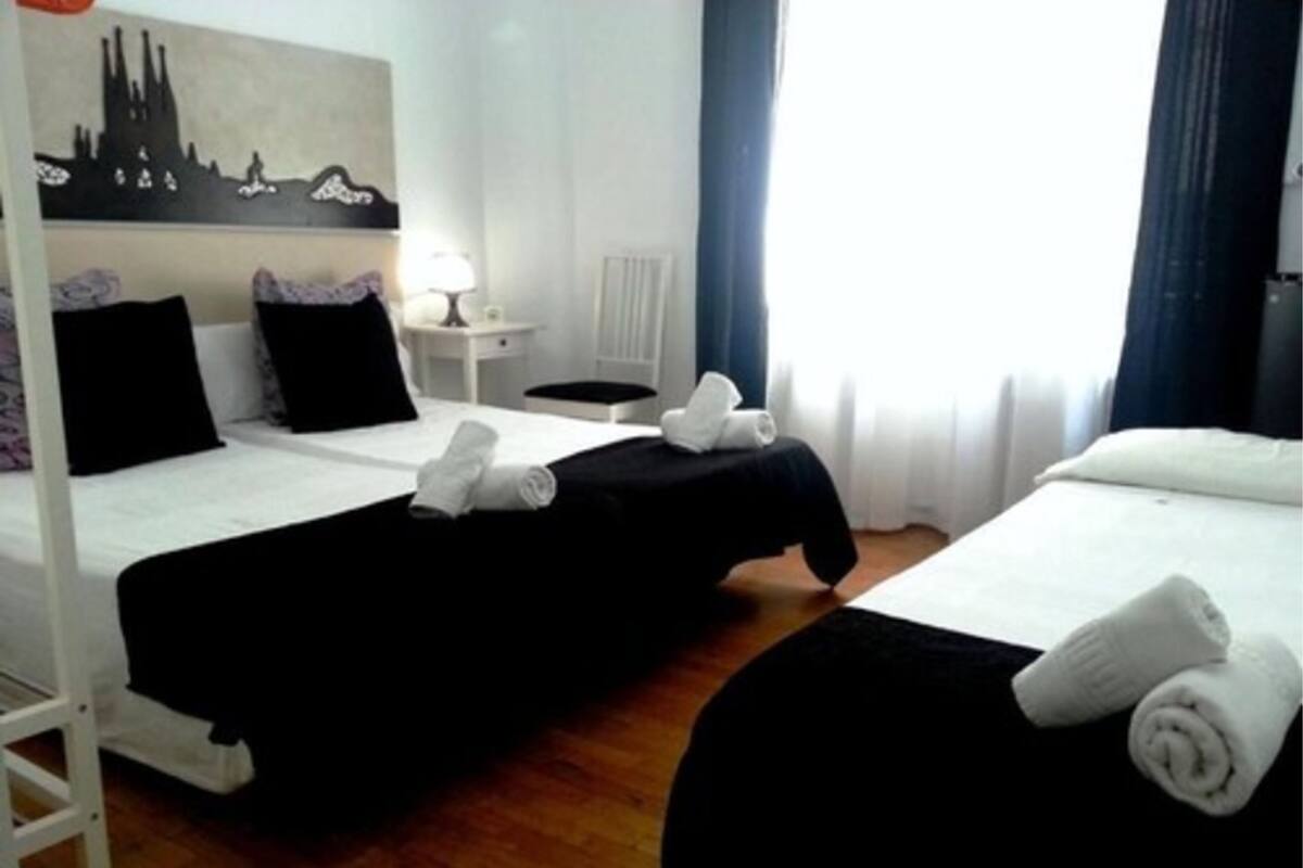 Habitación de hotel con dos camas, una mesita de noche, una lámpara y un cuadro en la pared.