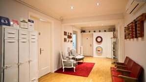 A hotel lobby with lockers, a reception desk, a red carpet, and a seating area with chairs. - Petit Hotel (Barcelona)