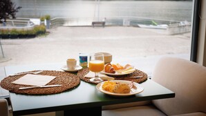 A breakfast table with plates of food, a glass of orange juice, and a cup of coffee. - Hotel Folgosa Douro (Armamar)