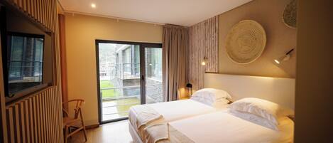 A modern hotel room with two beds, a large window, and a view of the outside.