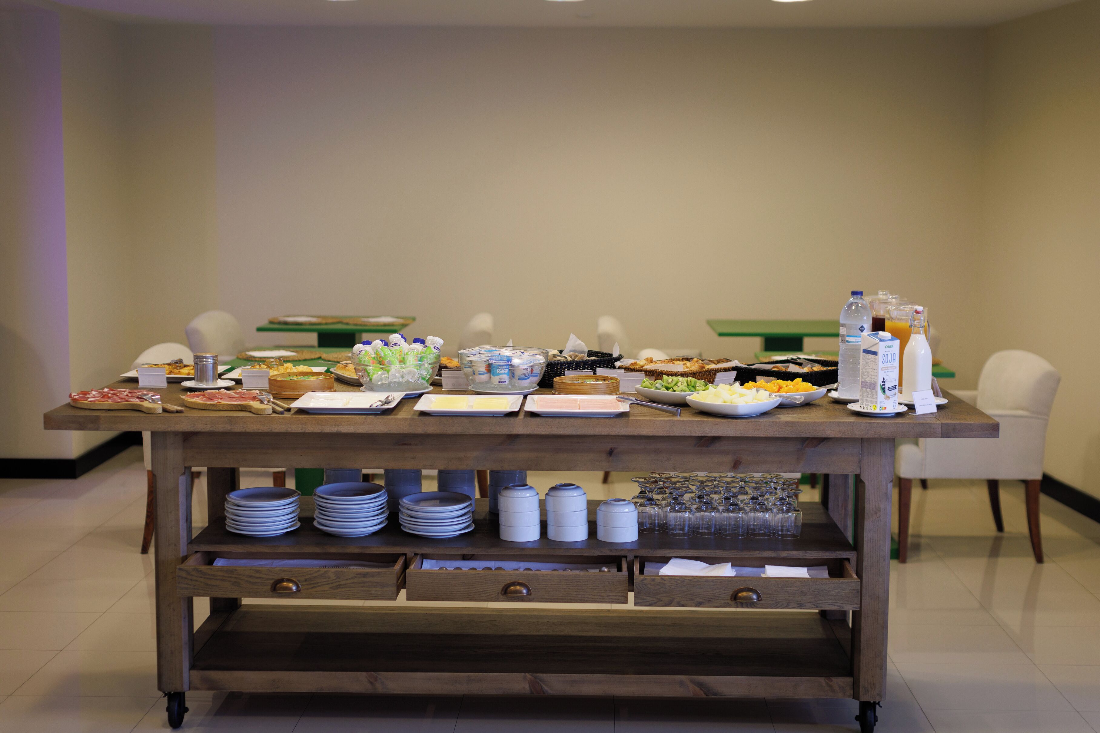 Une table de buffet proposant divers plats et boissons, ainsi que des assiettes, des bols et des récipients.