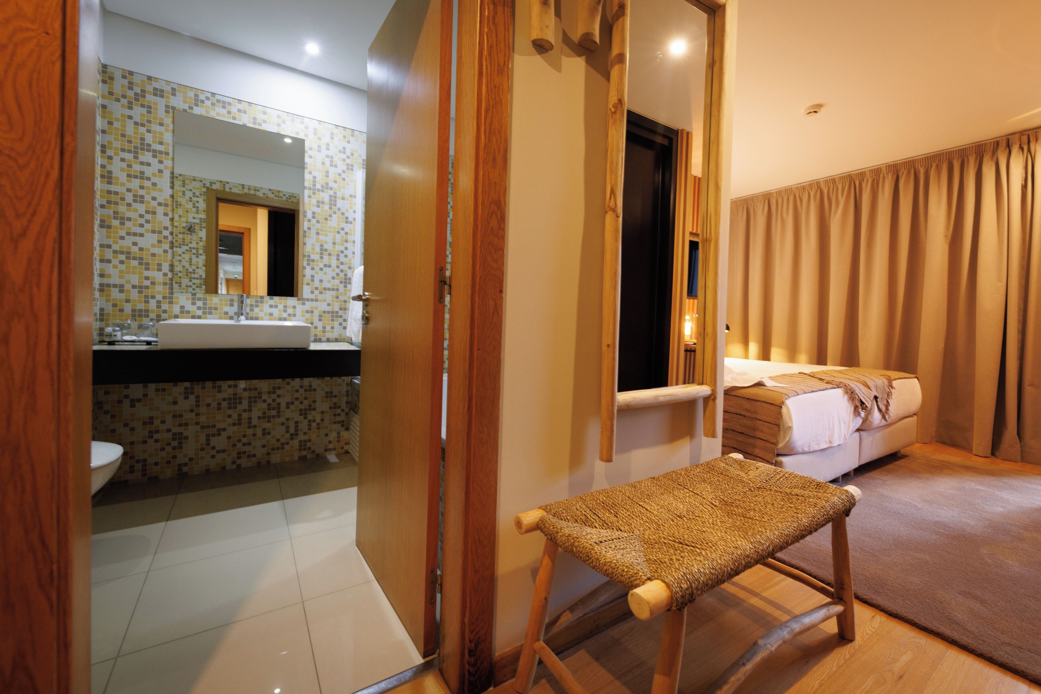 Una habitación de hotel con baño, cama y una banca.