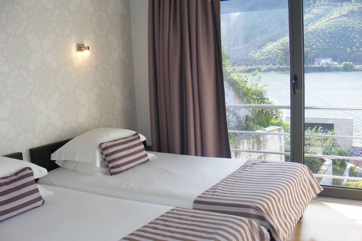 A hotel room with a large bed, a view of a body of water, and a balcony.