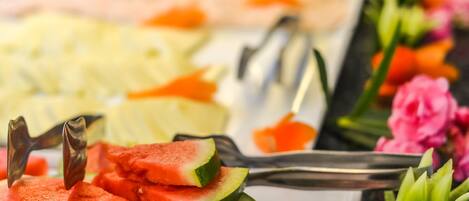 A buffet with various food items including watermelon slices and a rose-shaped dessert.