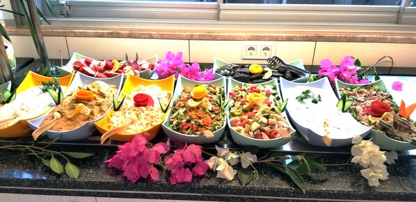 Buffet com diversos pratos e flores frescas.