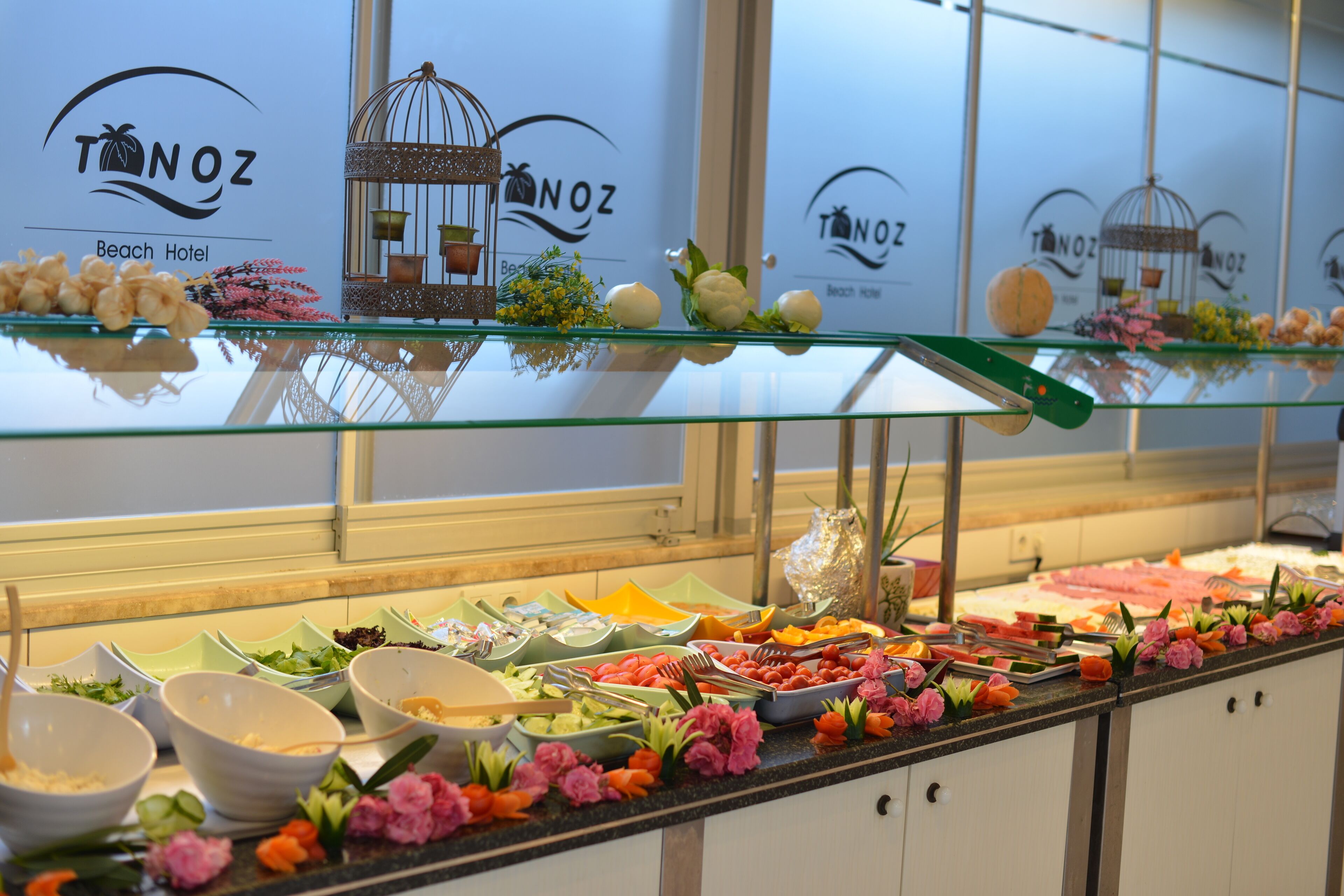 A buffet area with various food items and decorations, including flowers and a birdcage.