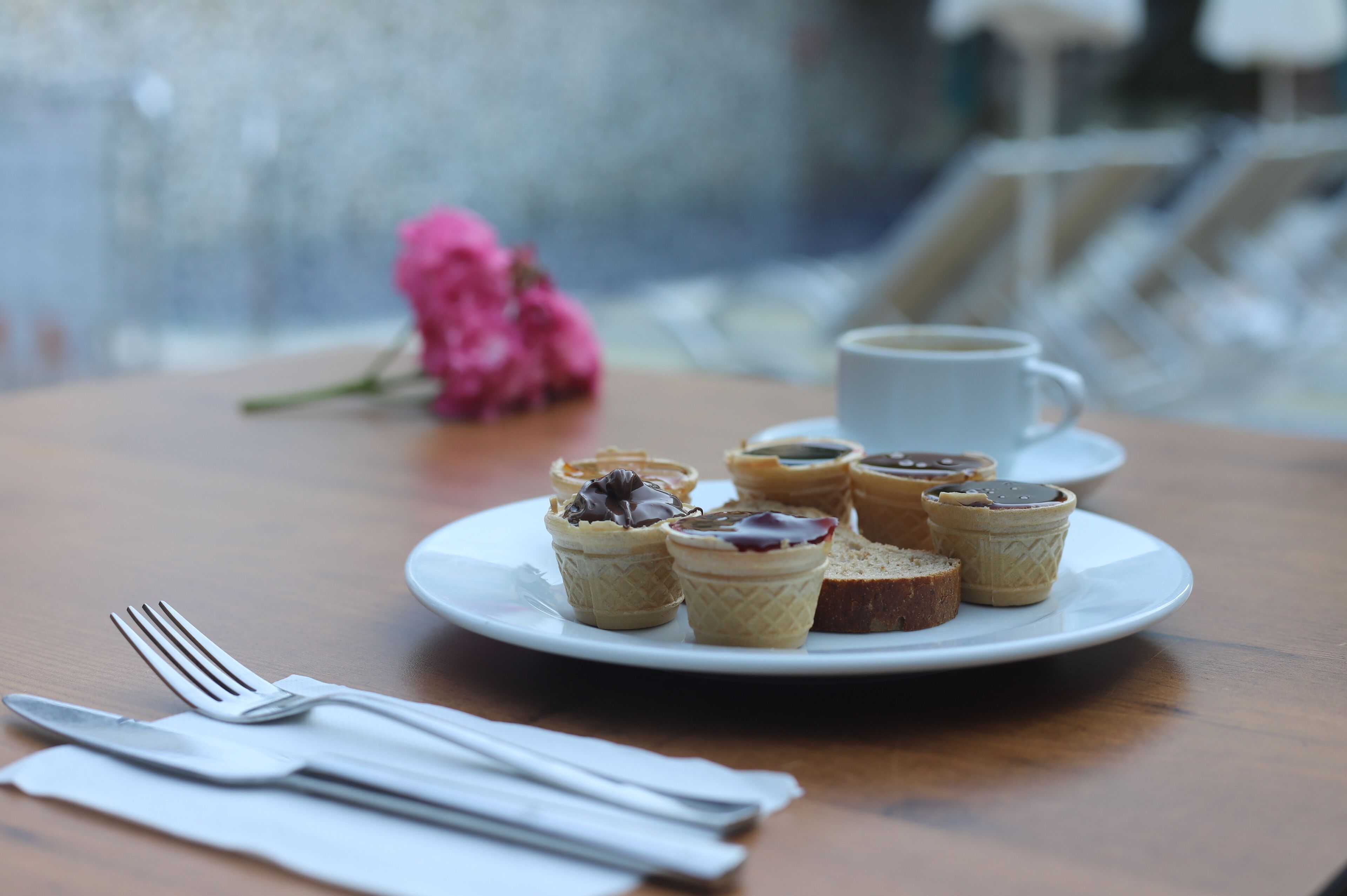 A plate of mini pastries on a table with a cup of coffee and a fork.