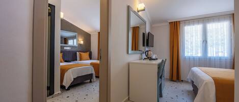 Habitación de hotel con dos camas, un escritorio, un espejo, un televisor y una ventana con cortinas.