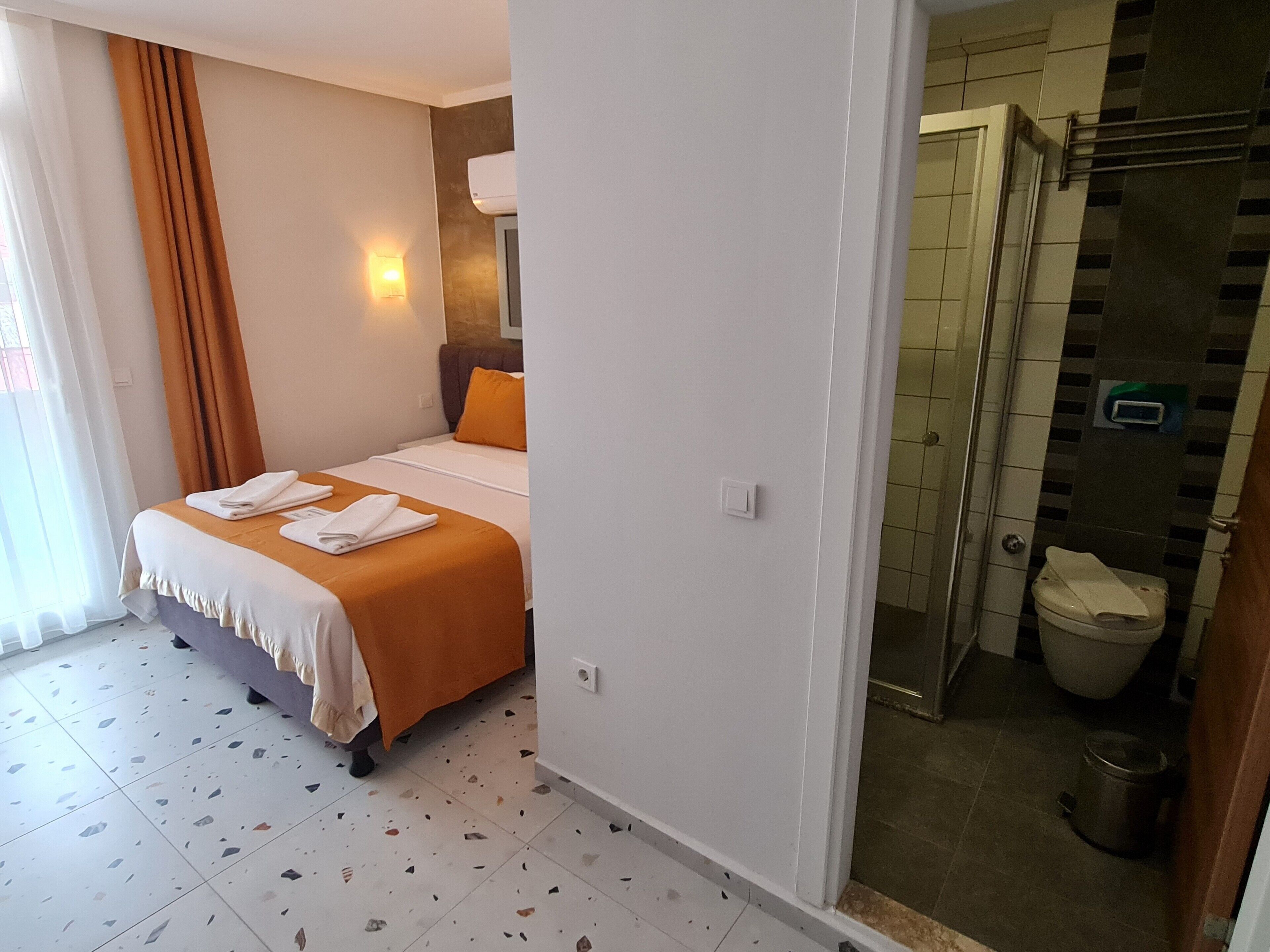 Habitación de hotel con cama, baño y zona de ducha.