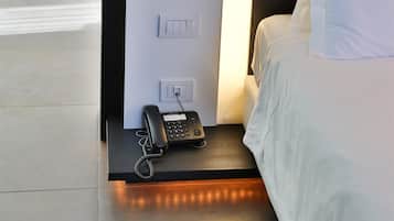 A hotel room with a bed, bedside table, and a phone.