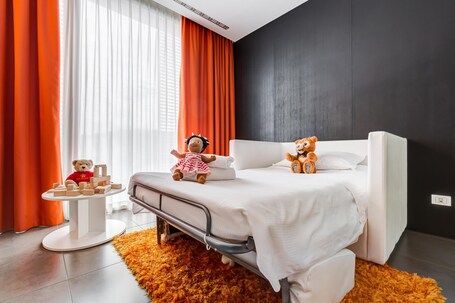 A hotel room with a bed, a small round table, and two teddy bears.