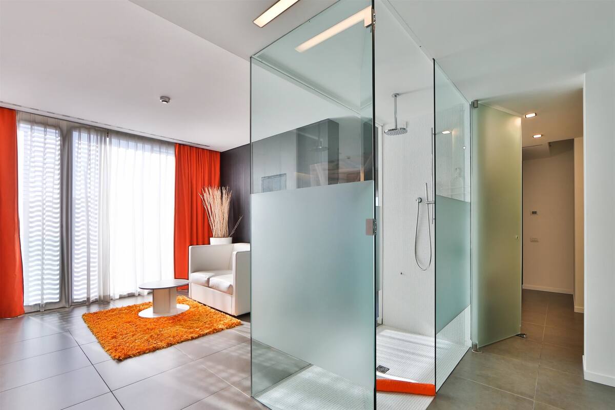 A modern bathroom with a glass partition, a shower, and a toilet.