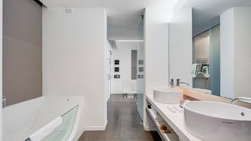 Un bagno moderno con due lavabi, uno specchio grande e un box doccia in vetro.