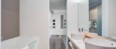 Un baño moderno con dos lavamanos, un espejo grande y una cabina de ducha de vidrio.