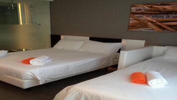 A hotel room with two beds, each with white linens and rolled towels, a large mirror, and a wall-mounted artwork.