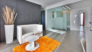 Eine moderne Hotellobby mit einem weißen Sofa, einem runden weißen Tisch und einem leuchtend orangefarbenen Teppich.