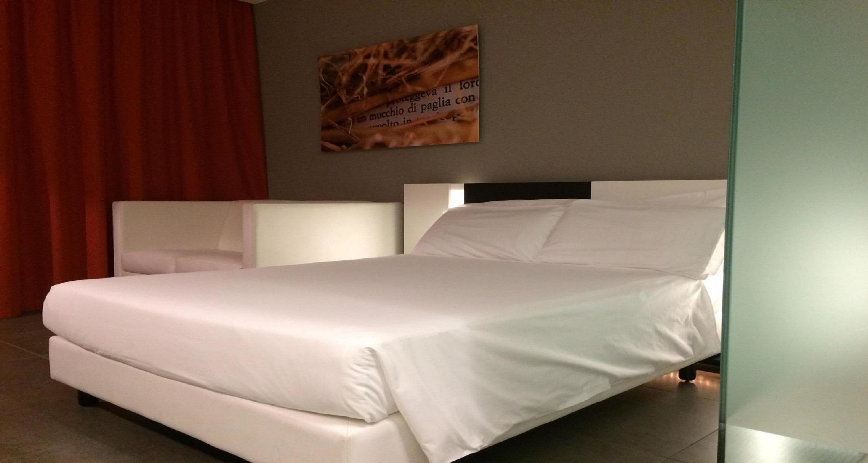 A modern bedroom with a large bed, a headboard, and a wall-mounted artwork.