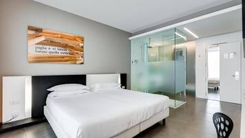 Een moderne hotelkamer met een groot bed, een glazen douchecabine en een wanddecoratie.