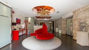 Un vestíbulo moderno con un sofá rojo, una araña y una pared de piedra.
