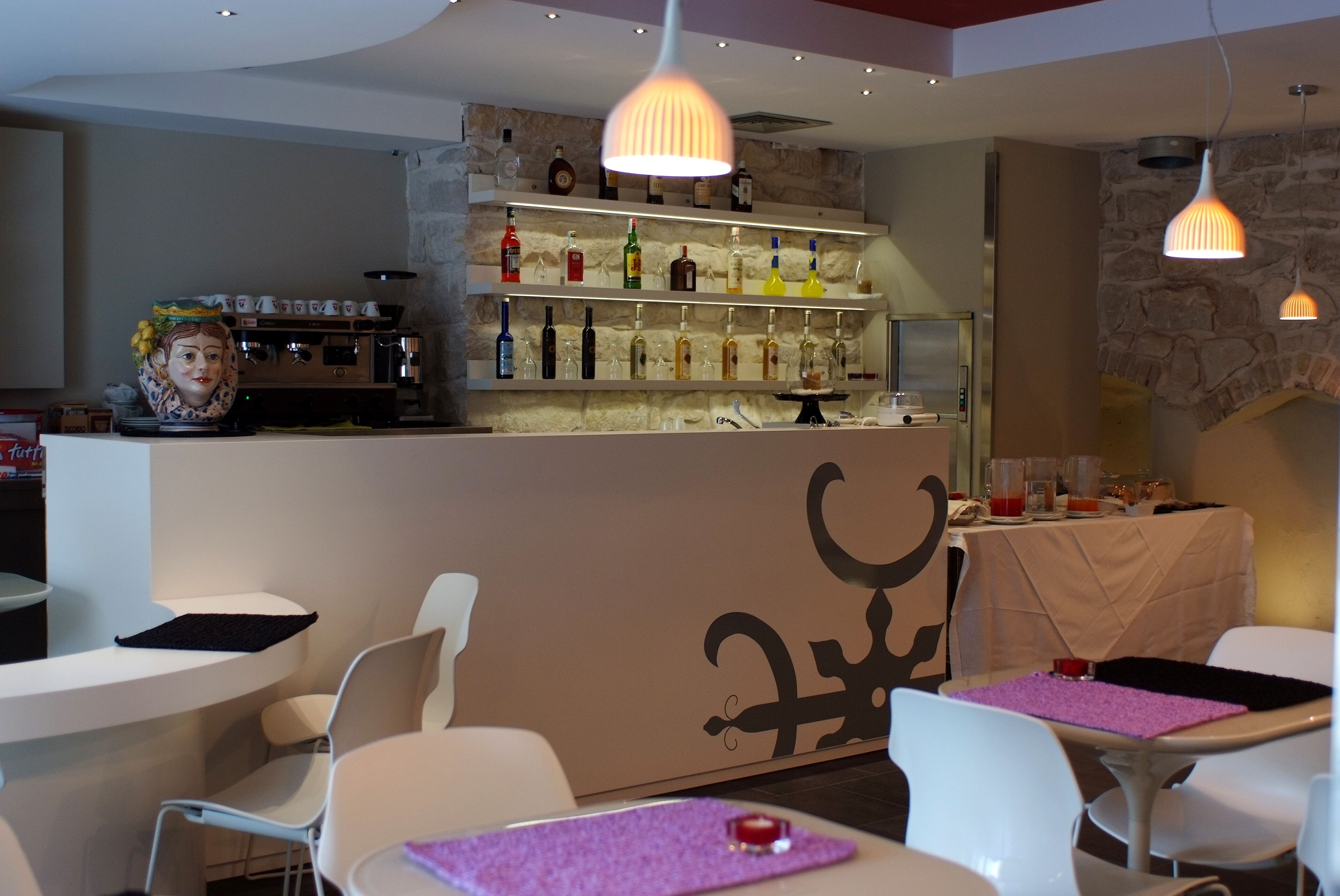 Un restaurante con área de bar, sillas blancas y mesas con manteles individuales morados.
