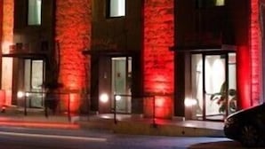 Un edificio de varios pisos con fachada iluminada en rojo y numerosas ventanas.