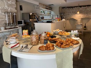 A breakfast buffet with pastries, fruits, and beverages. - Hotel El Homs Palace (Comiso)