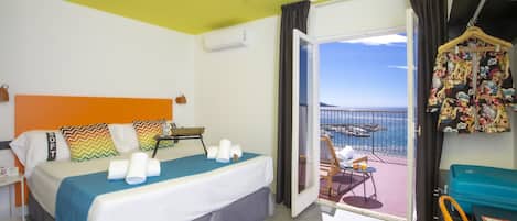 A hotel room with a bed, a balcony with a view, and a hanging garment rack.