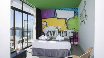 A modern hotel room with a large bed, a small desk, a chair, and a view of the outdoors.