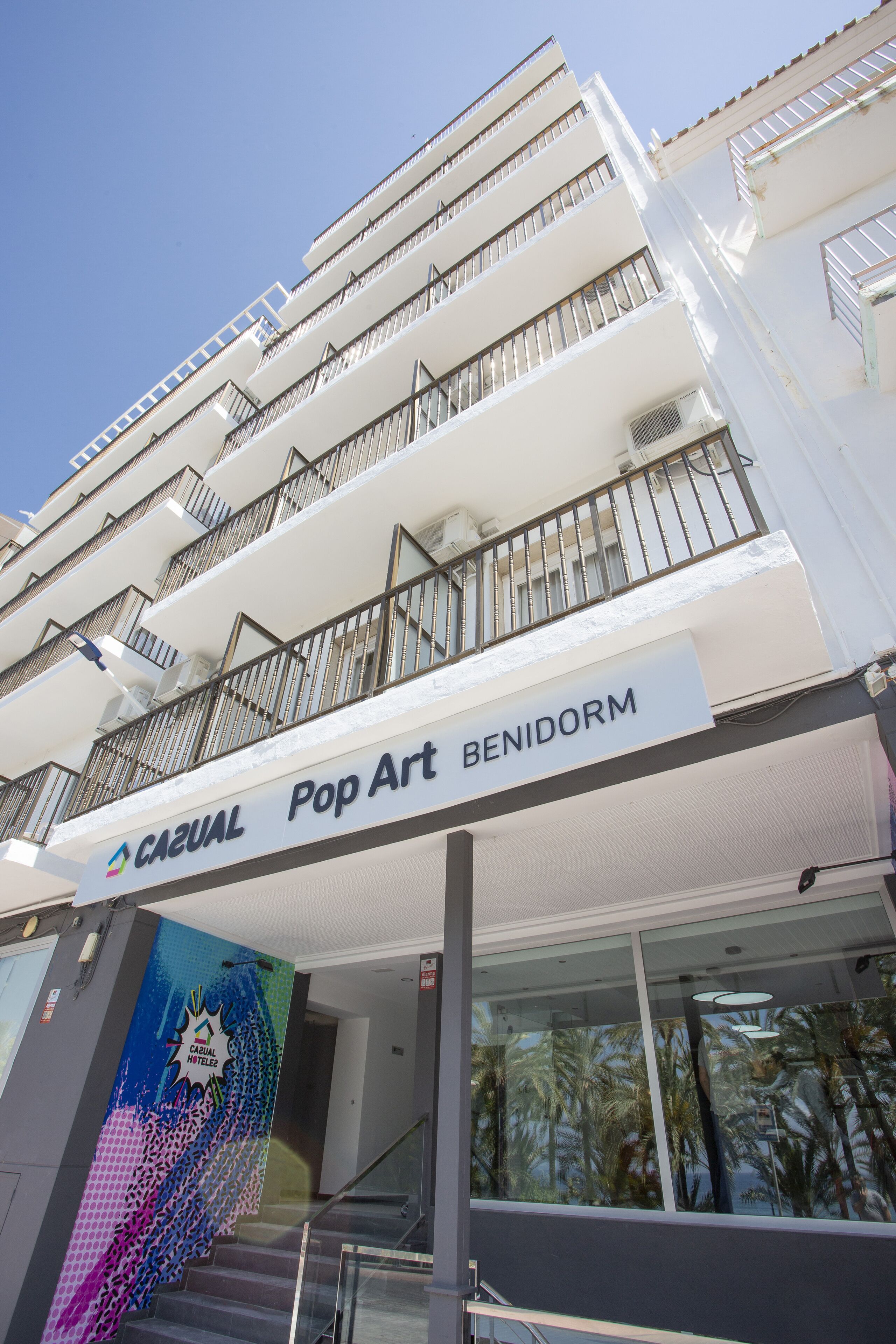 A hotel with a white facade, balconies, and a sign for 'CAZUAL Pop Art BENIDORM'.