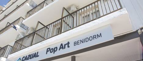 A hotel with a white facade, balconies, and a sign for 'CAZUAL Pop Art BENIDORM'.