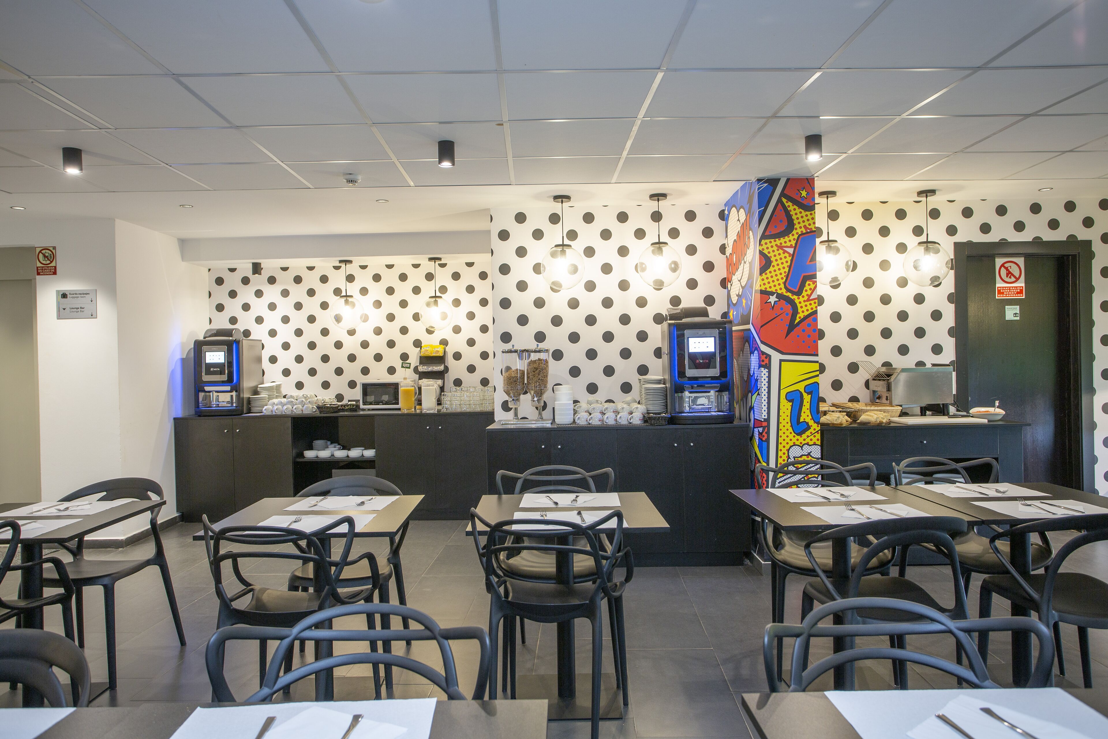 A restaurant with a polka dot wall, tables, chairs, and a colorful mural.