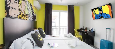 A hotel room with two beds, a desk, a chair, a suitcase, and artwork on the walls.