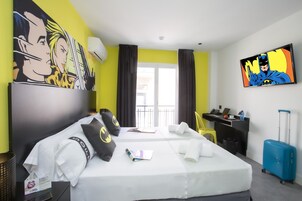 Ein Hotelzimmer mit zwei Betten, einem Schreibtisch, einem Stuhl, einem Koffer und Bildern an den Wänden.