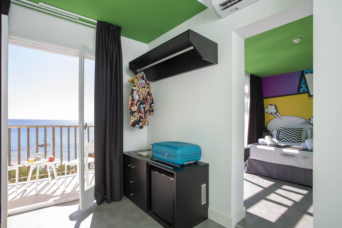 A room with a balcony, a bed, a desk, and a wardrobe.