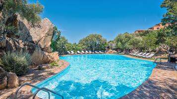 Una piscina al aire libre, sillones reclinables de piscina