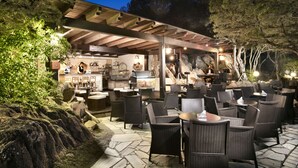 An outdoor patio area with wicker furniture and a bar area. - Hotel Rocce Sarde (Olbia)