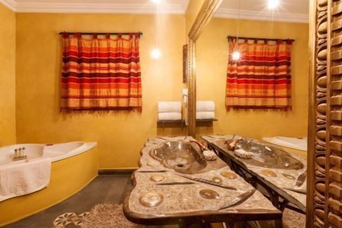 Ein Badezimmer mit einem Steinkonfett, zwei Waschbecken und einem großen Spiegel.