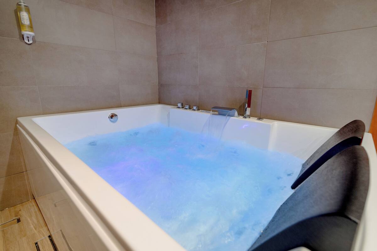 Une salle de bain moderne avec une grande baignoire, un chauffe-eau apparent et un porte-serviettes.