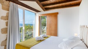 A bedroom with a large window, a bed with white linens, and a view of the outdoors. - Mas Ses Vinyes - Adults Only (Begur)