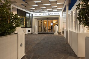 A hotel entrance with a stone-paved pathway leading to a glass door.