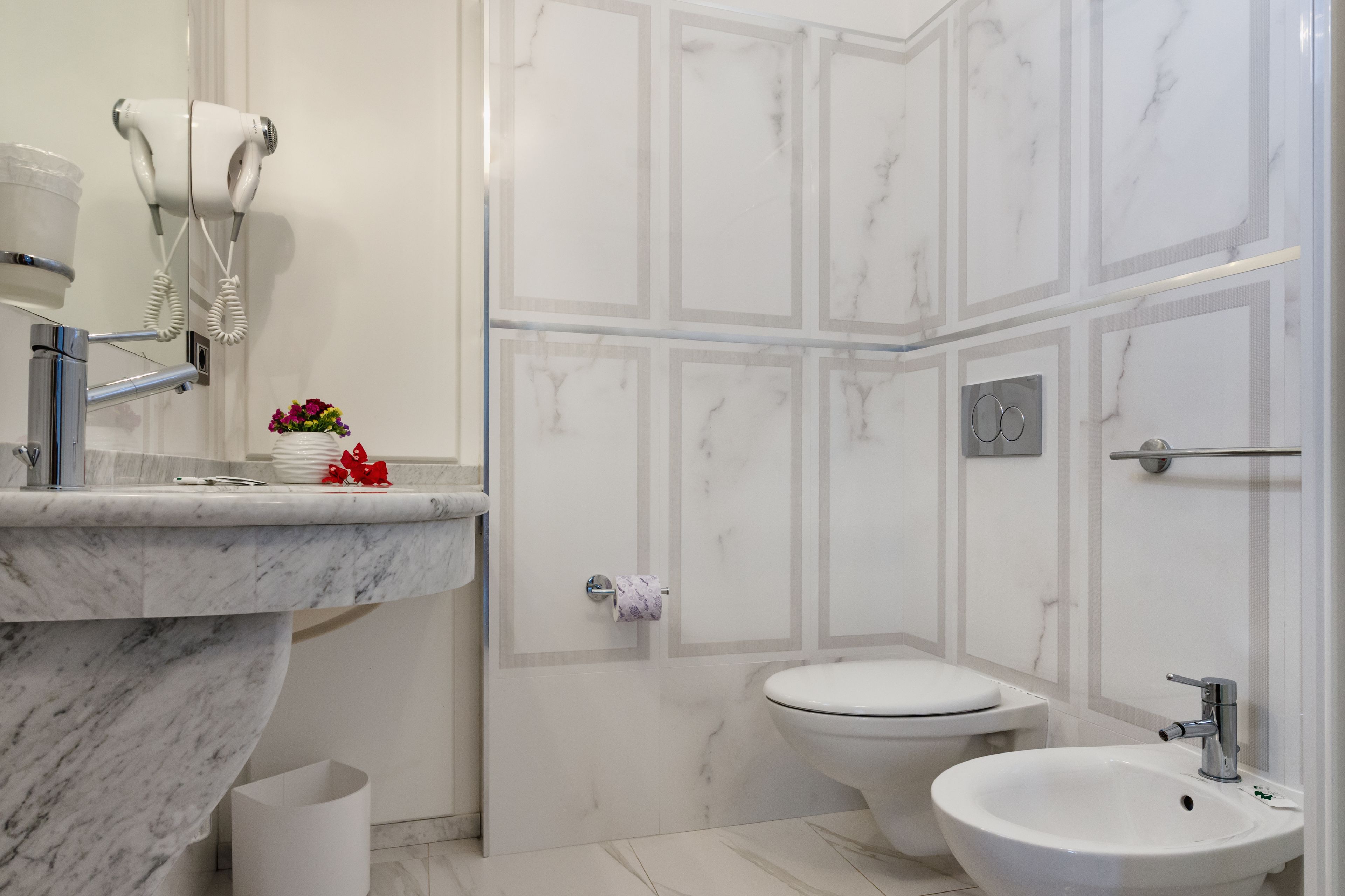 A modern bathroom with a marble sink, a toilet, a bidet, and a shower area.