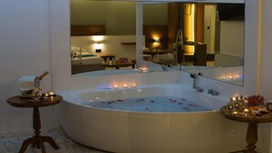 Une salle de bain moderne avec une grande baignoire sur pieds, un grand miroir et une petite table avec des bougies.