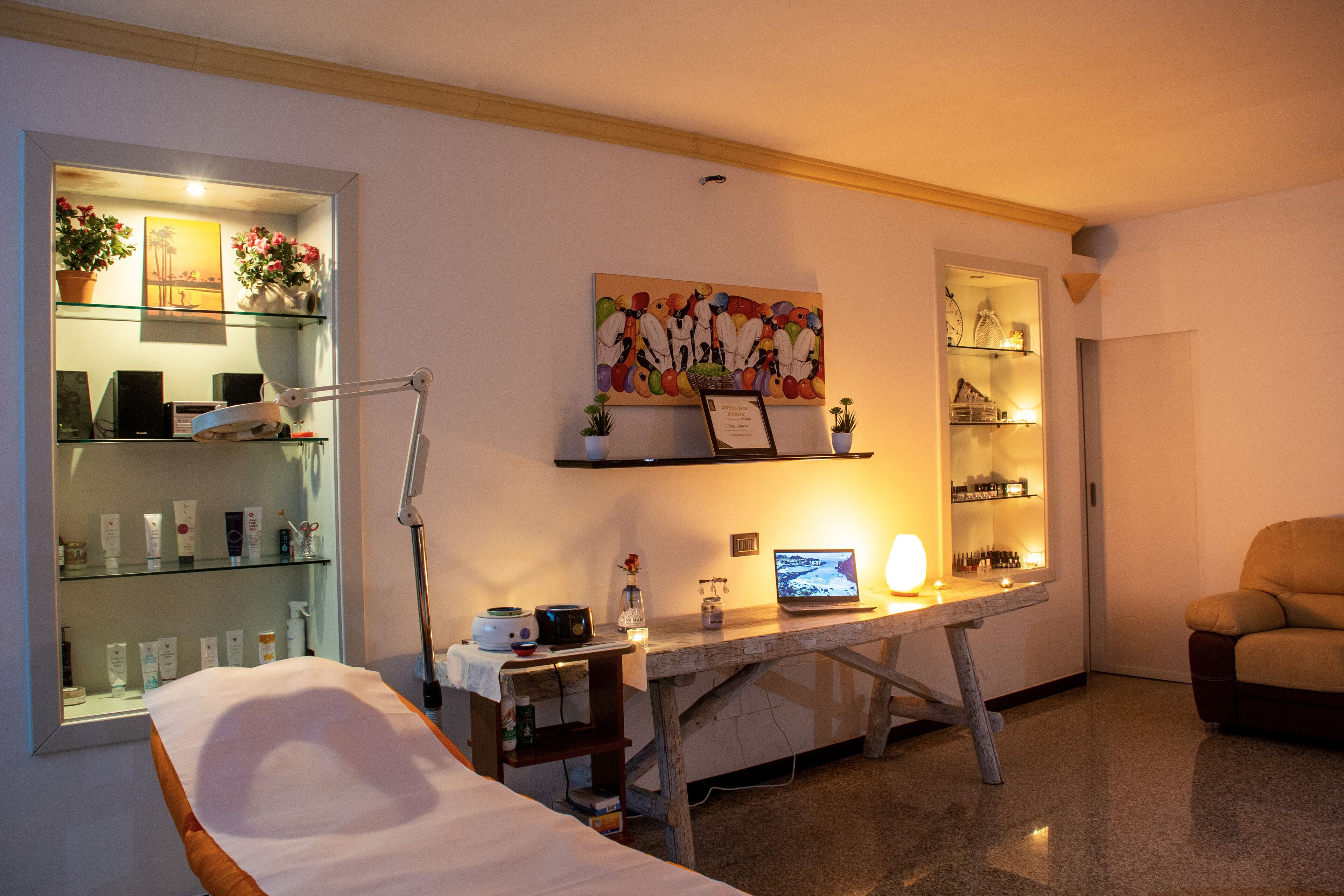 Ein Zimmer mit einem Bett, einem Schreibtisch mit Computer, Regalen mit diversen Gegenständen und einem Bild an der Wand.