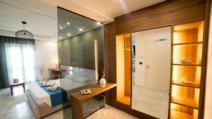 Une chambre d’hôtel moderne, équipée d’un lit, d’une table de chevet et d’une étagère en bois intégrée, agrémentée d’objets décoratifs.
