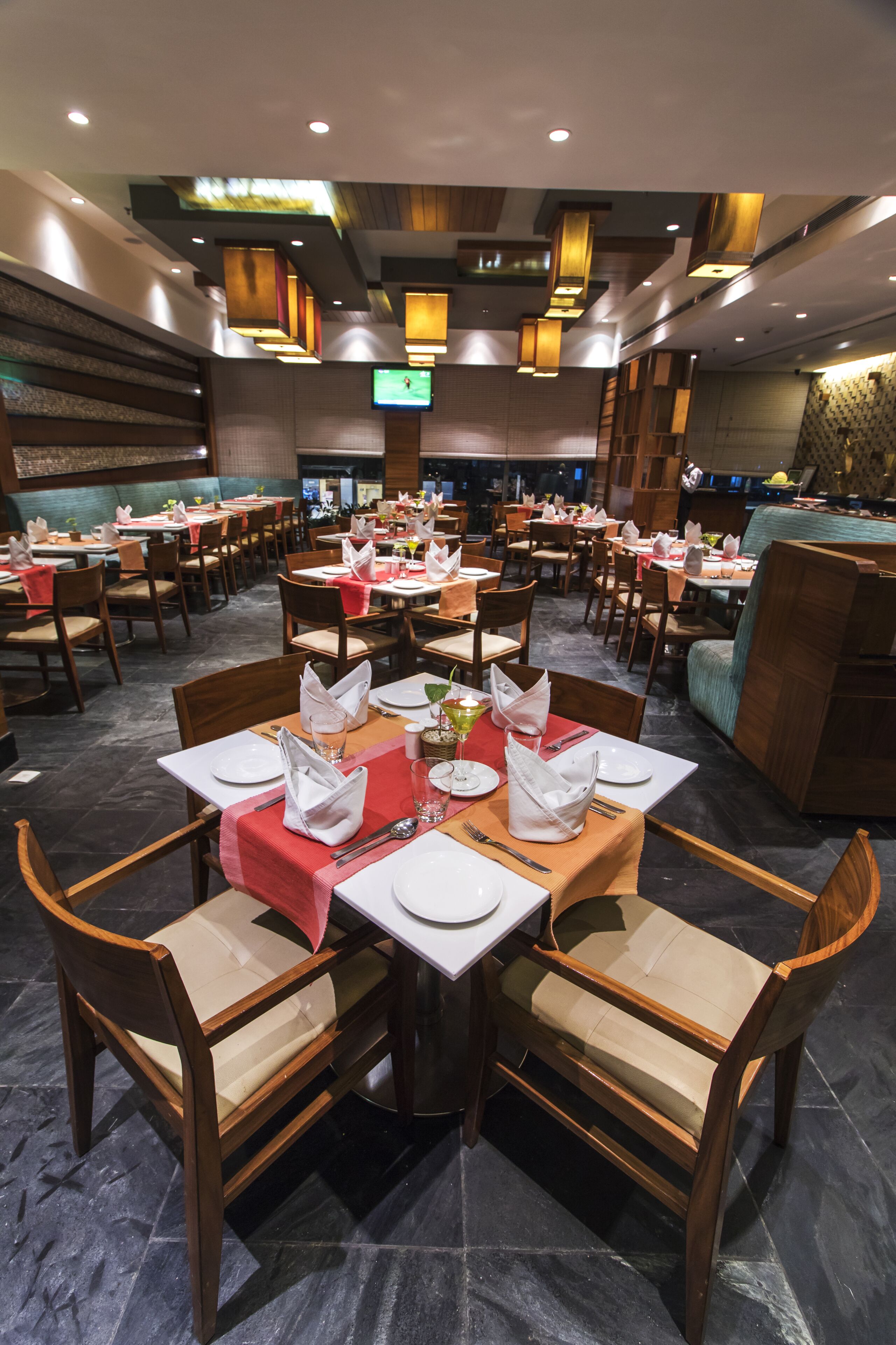 Una sala ristorante con diversi tavoli apparecchiati, complete di sedie e stoviglie.