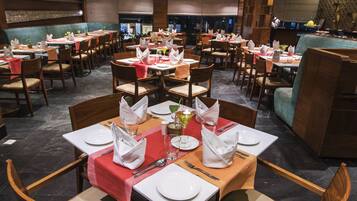 Una sala ristorante con diversi tavoli apparecchiati, complete di sedie e stoviglie.