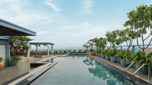 Una piscina en la azotea con vistas despejadas del horizonte de la ciudad, rodeada de plantas en macetas y mobiliario de exterior.