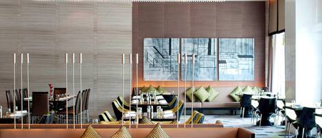 A modern dining area with a long table, chairs, and a sofa.