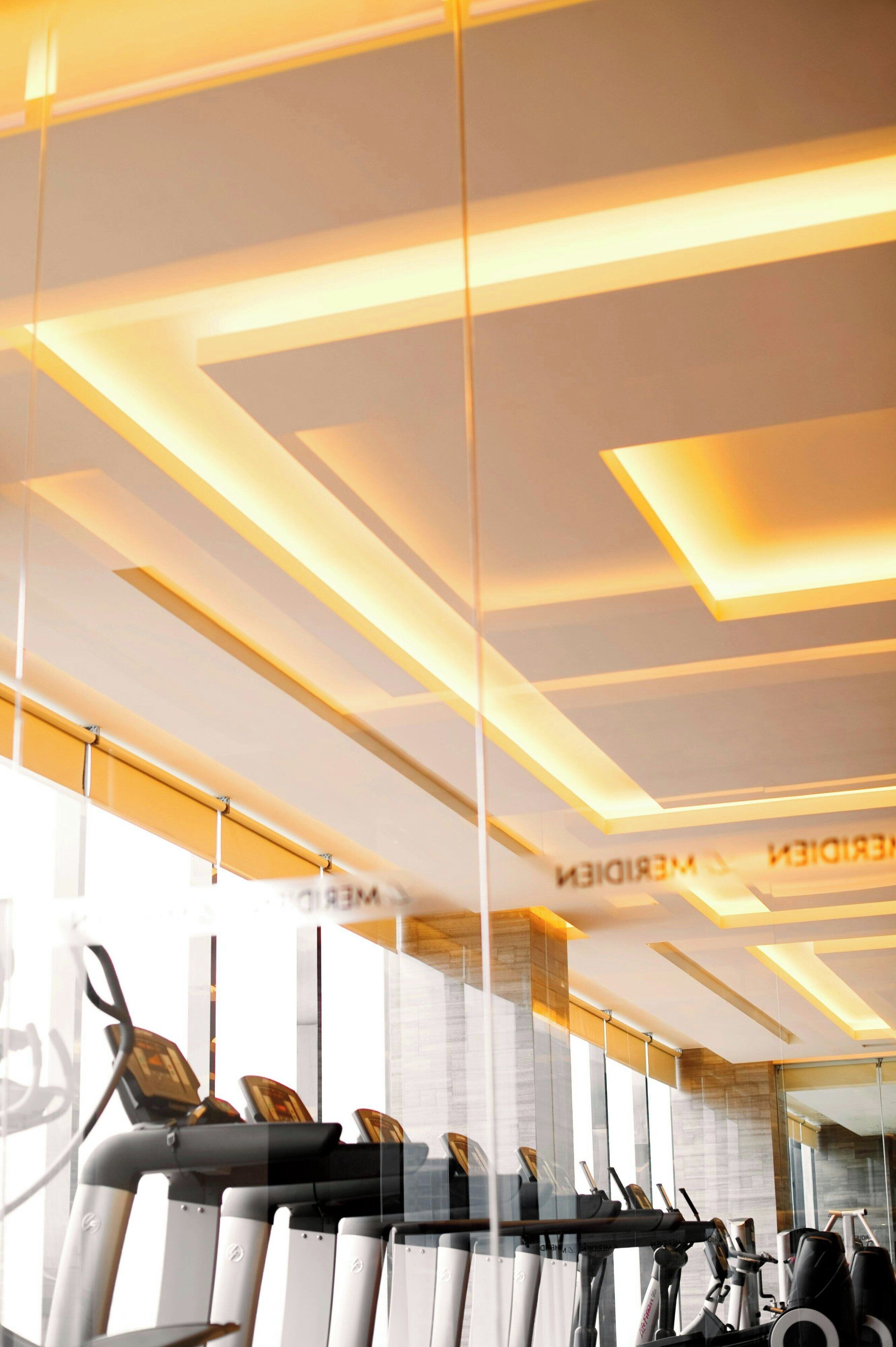 A gym with exercise equipment and a modern ceiling design.