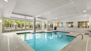 An indoor swimming pool with clear water, surrounded by white tiled walls and a ceiling with recessed lighting. - Hilton Garden Inn Atlanta Airport North (Atlanta)